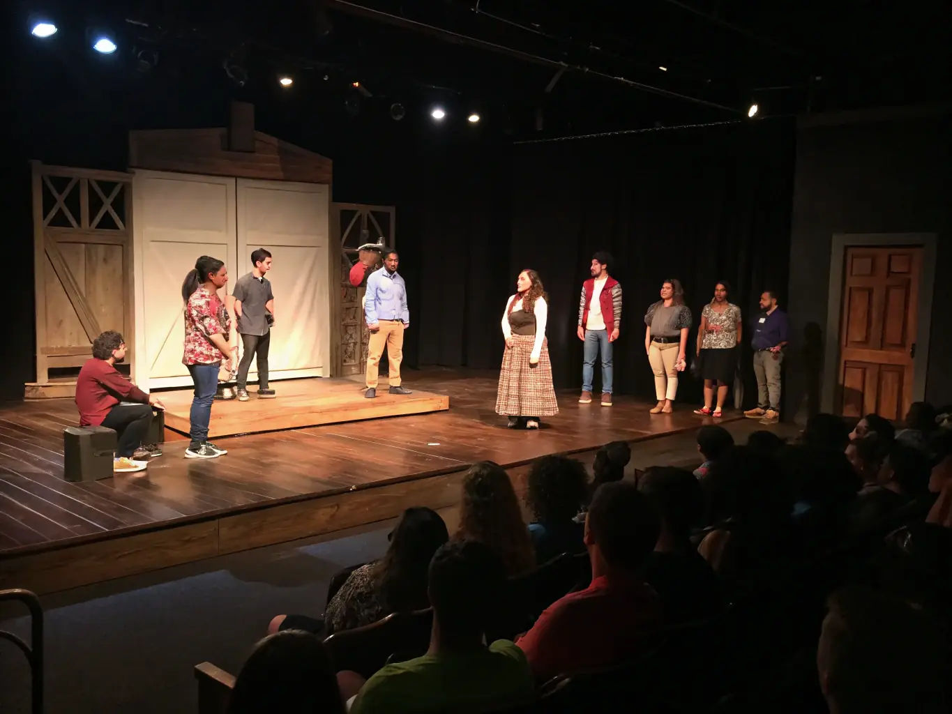 A vibrant photograph capturing a community theater workshop in progress, with participants actively engaged in a scene rehearsal, showcasing the organization's commitment to performing arts education.